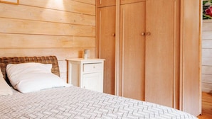 A bedroom with a wooden wall, a bed with white bedding, a nightstand, and a wardrobe. - Chalet with Jacuzzi and Terrace in Bormes-les-Mimosas (Bormes-les-Mimosas)