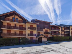 Une rangée d’immeubles à plusieurs étages dotés de balcons, un petit bâtiment d’entrée et un ciel dégagé.