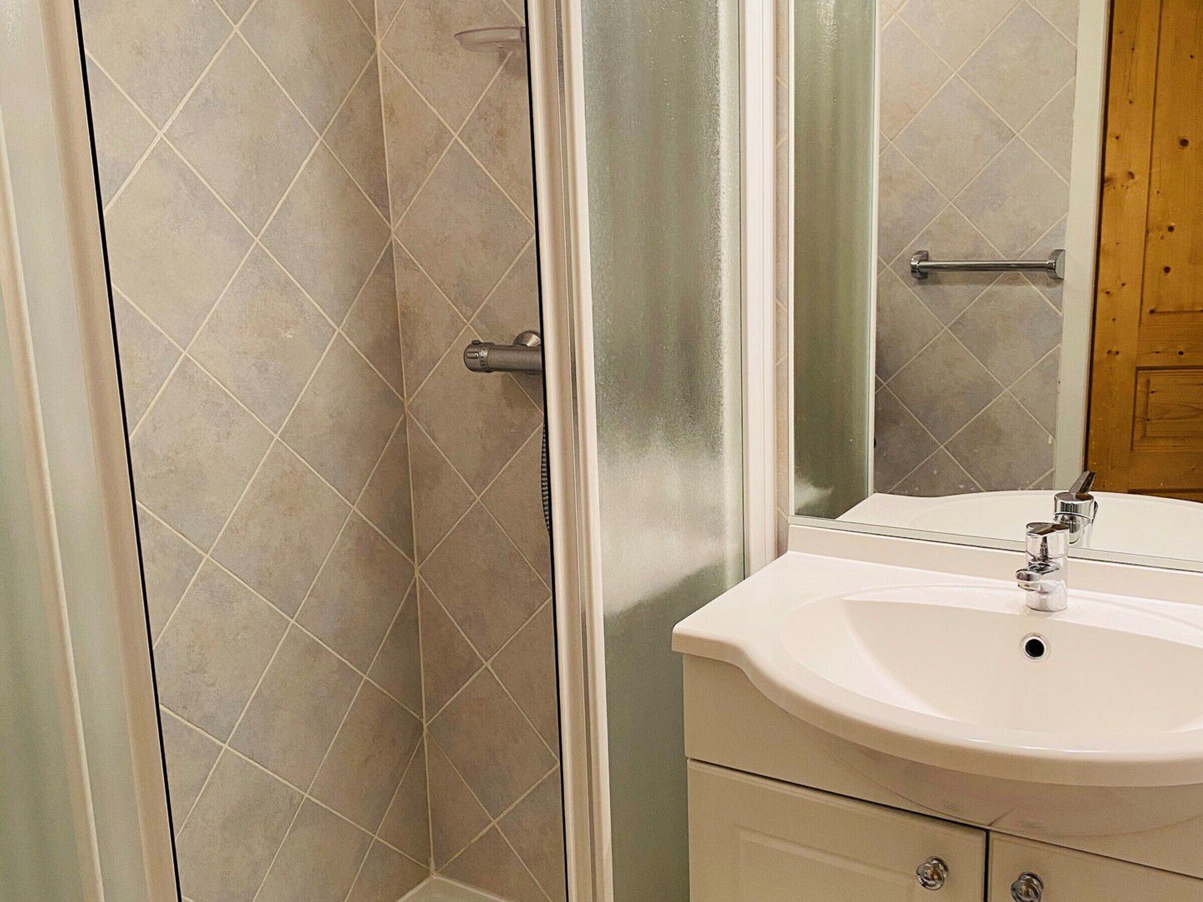Ein Badezimmer mit Dusche, Waschbecken und Spiegel.