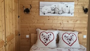Habitació de cabana de fusta amb un llit, naxres amb dibuixos de cor i una fotografia d'ós polar a la paret.