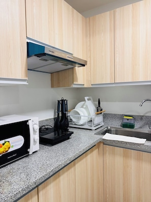 Una cocina con armarios de madera, microondas, escurreplatos y fregadero.