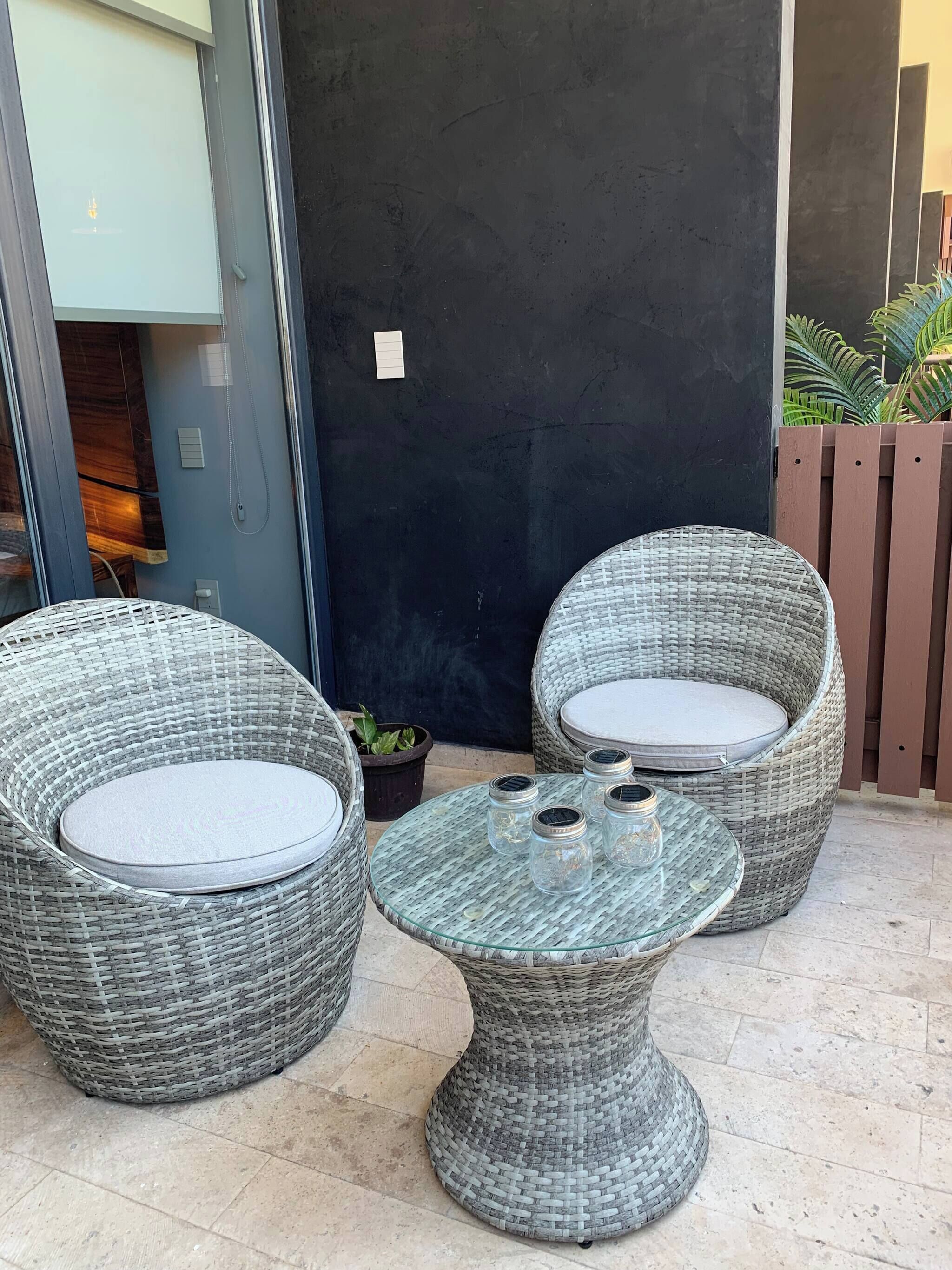 Wicker furniture with cushions, a glass table, and a potted plant.