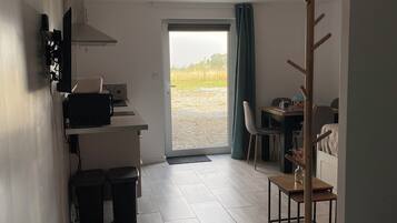 A compact room with a kitchenette, a dining area, and a view through a sliding door.
