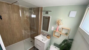 Un bany modern amb dutxa envidriada, un lavabo blanc i un vàter.