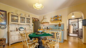 Un coin repas avec une table verte, quatre chaises, un réfrigérateur et une cuisine en arrière-plan.