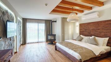 Een slaapkamer met een houten plafond, een groot bed, een televisie en een open haard.