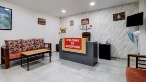 A reception area with a 'Welcome to Reception' sign, a sofa, a desk, and a wall with framed pictures. - S M Suites (Bengaluru)