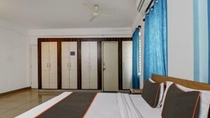 A hotel room with a bed, a ceiling fan, and a wardrobe with multiple doors. - S M Suites (Bengaluru)