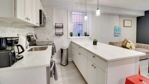 Une cuisine moderne avec des meubles blancs, un îlot central et des luminaires suspendus.