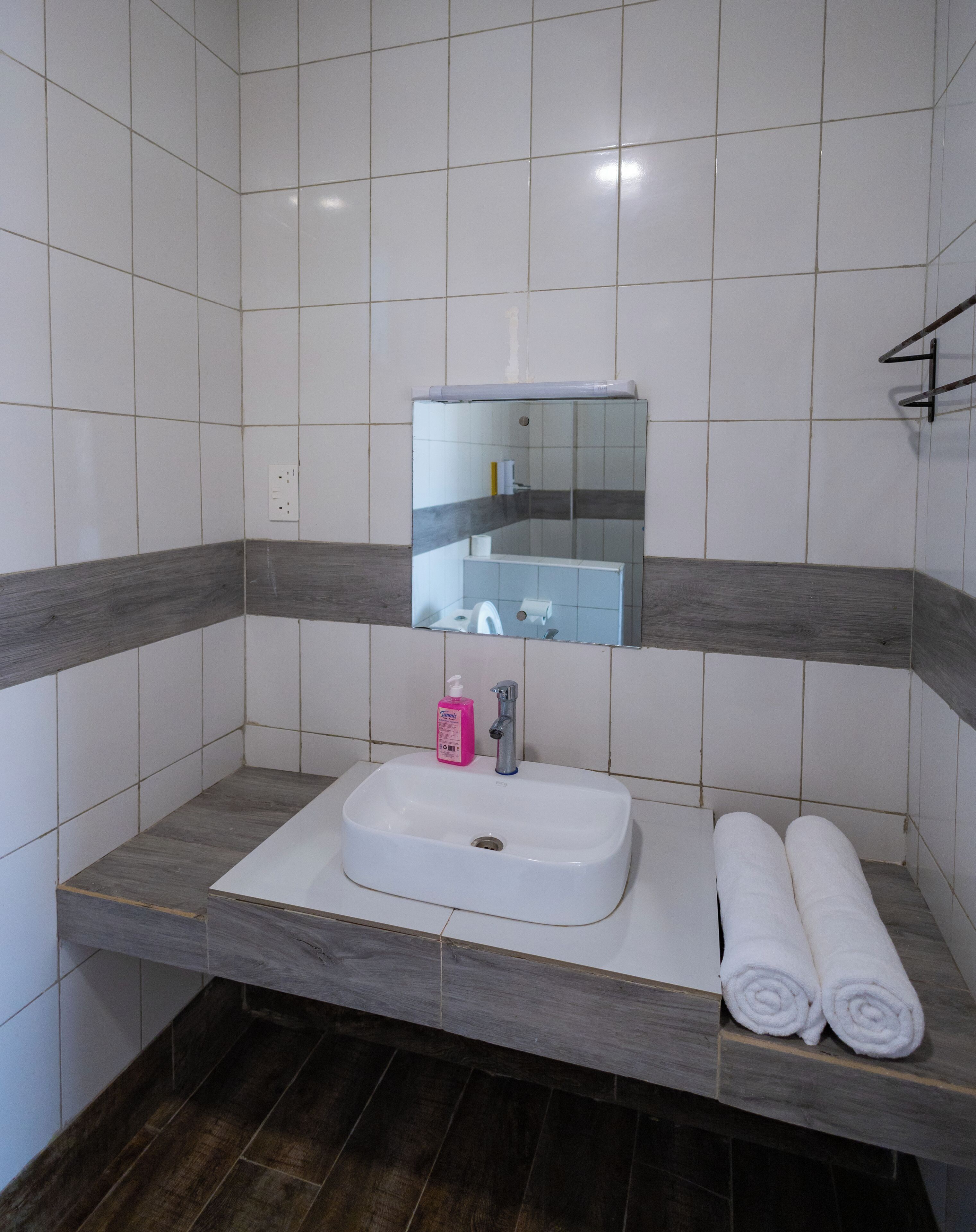 A bathroom with a white sink, a mirror, and a towel rack.