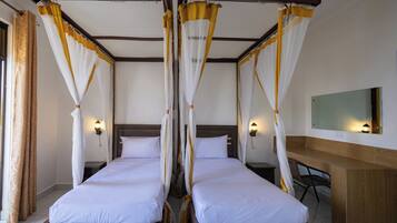 A room with two beds, each with a canopy, a wooden headboard, and a nightstand with a lamp.
