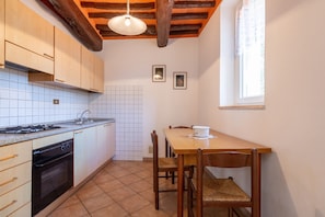 A kitchen with wooden cabinets, a stove, and a dining table with chairs.