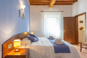 A neatly made bed with pillows, a bedside lamp, a folded towel, and a wooden headboard.