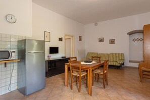 Una cucina compatta con frigorifero, microonde e tavolo con sedie.