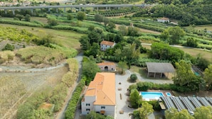 A rural property with a swimming pool, a covered outdoor seating area, and a bridge in the background. - Lavanda Apartment with Shared Pool and Garden (Rosignano Marittimo)