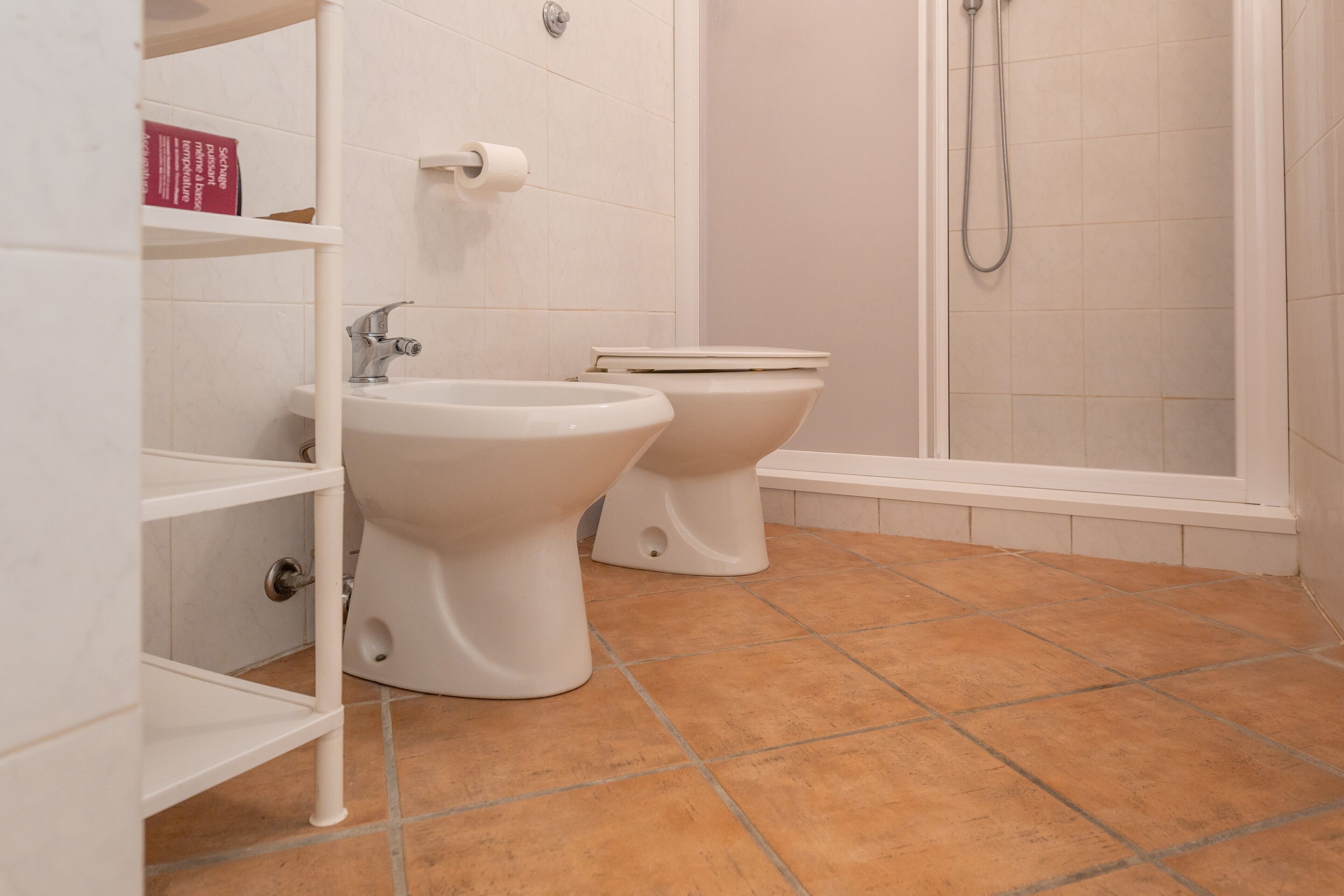 A bathroom with a bidet, a toilet, a sink, and a shower.