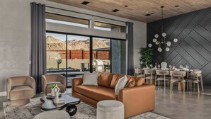 Ein modernes Wohnzimmer mit Sofa, Sesseln, einem Couchtisch und einem Essbereich mit einer Chandelüster.