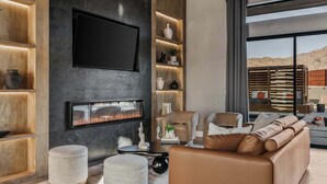Ein modernes Wohnzimmer mit Kamin, Ledersofa und großem Fenster mit Blick auf die Wüste.