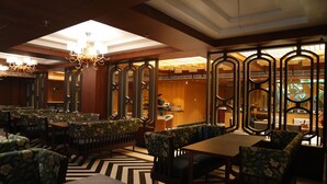 Ein Restaurant mit Sitzgelegenheiten in Form von Boxen und Tischen, Holzvertäfelung und einer Kristallleuchtre.