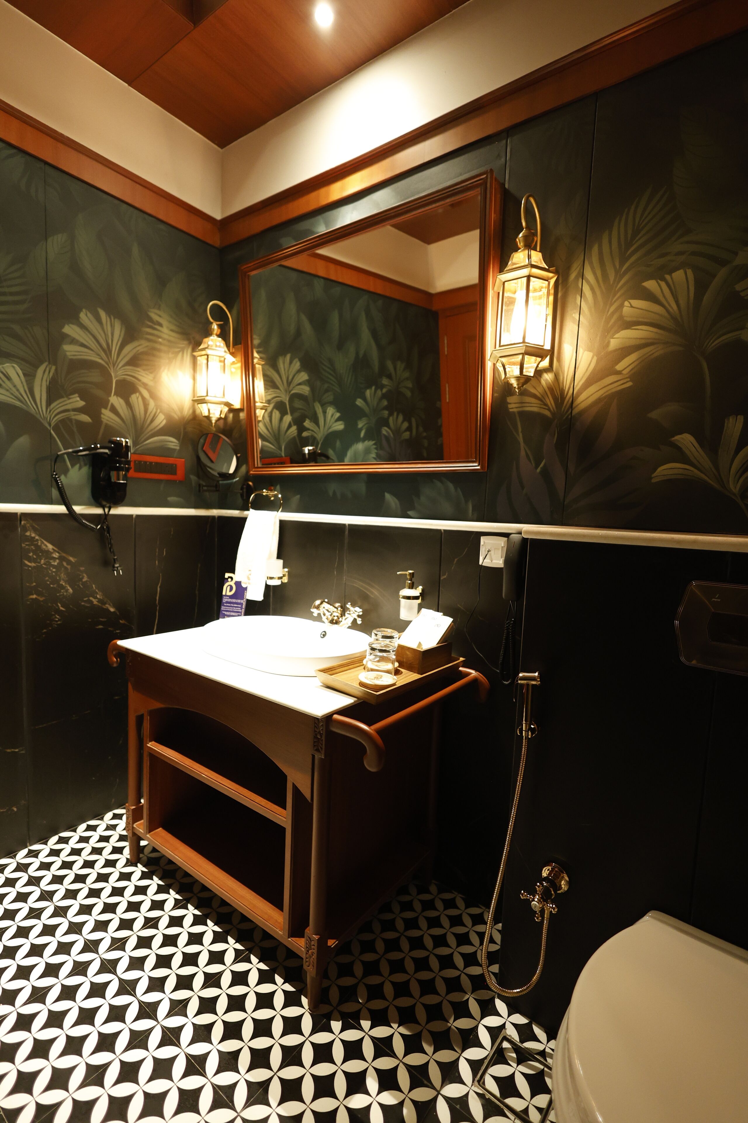 Un baño con tocador de madera, un espejo, dos luces empotradas, un inodoro y un suelo con estampado.
