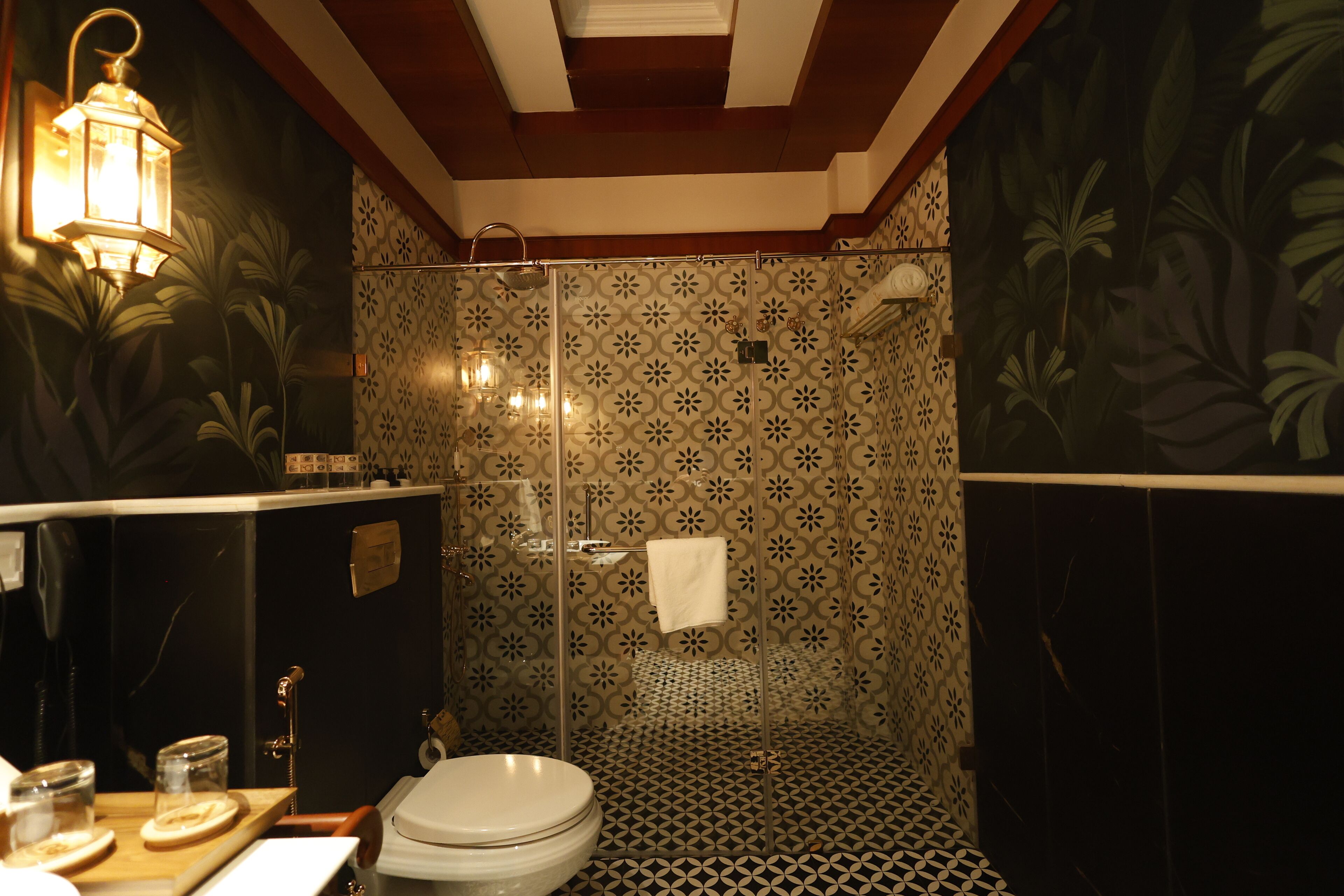 A bathroom with a patterned tile floor, a toilet, a sink, and a shower with a glass door.