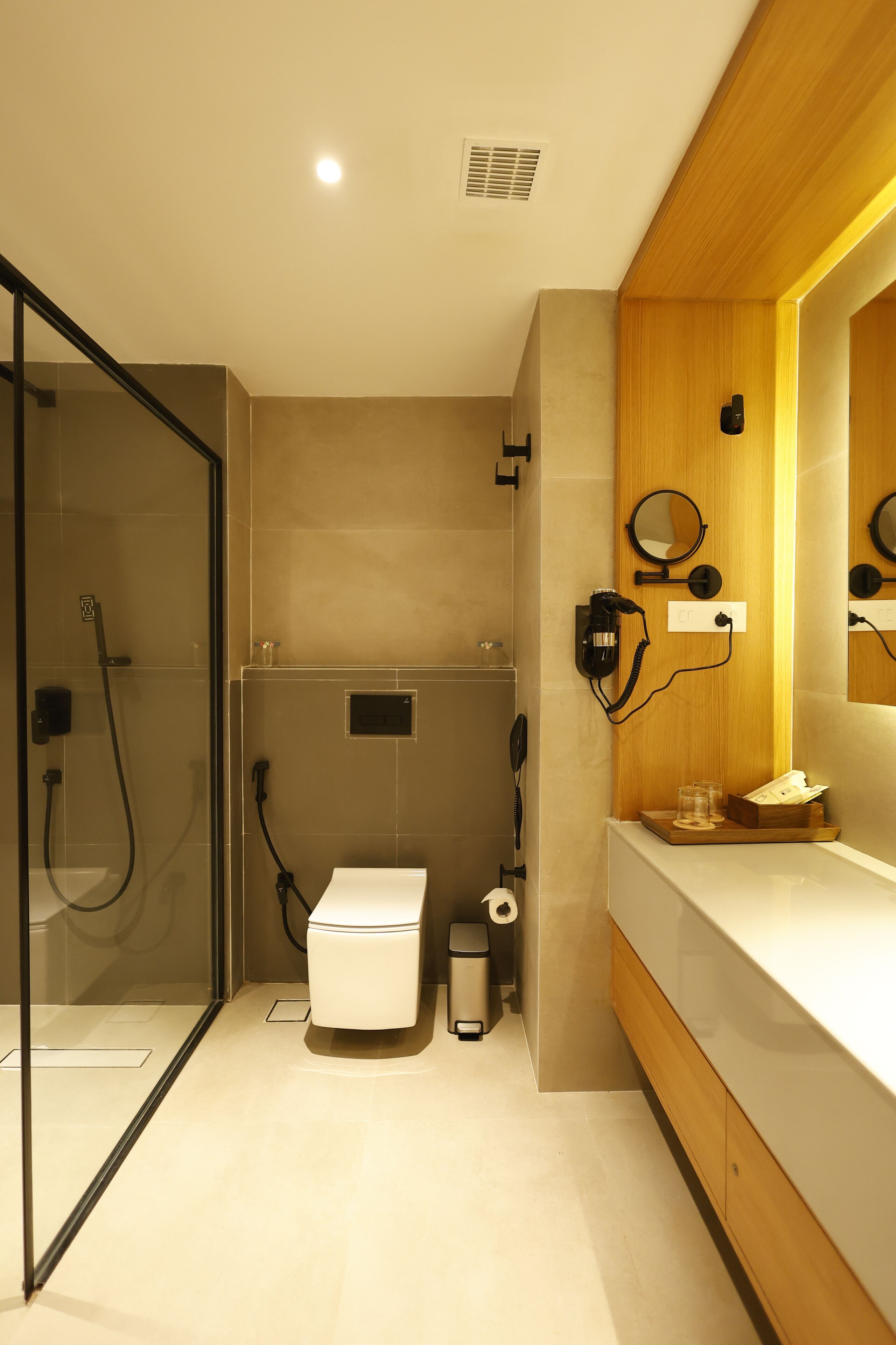 Une salle de bain moderne dotée d’une douche à parois de verre, de toilettes et d’un meuble-lavabo avec un miroir.