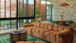 A modern living room with a large window, a sofa, a round table, and a patterned wall. - 5loft Anti-Hotel, Silom, Bangkok (Bangkok)