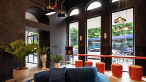 A modern interior with a blue sofa, potted plants, and orange stools near large windows. - 5loft Anti-Hotel, Silom, Bangkok (Bangkok)