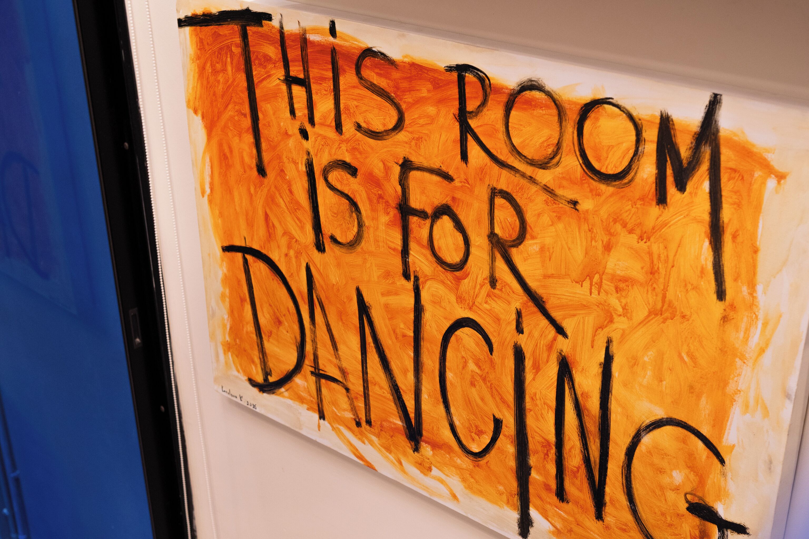 Una pared con un mensaje pintado en negro que dice 'THIS ROOM IS FOR DANCING'.
