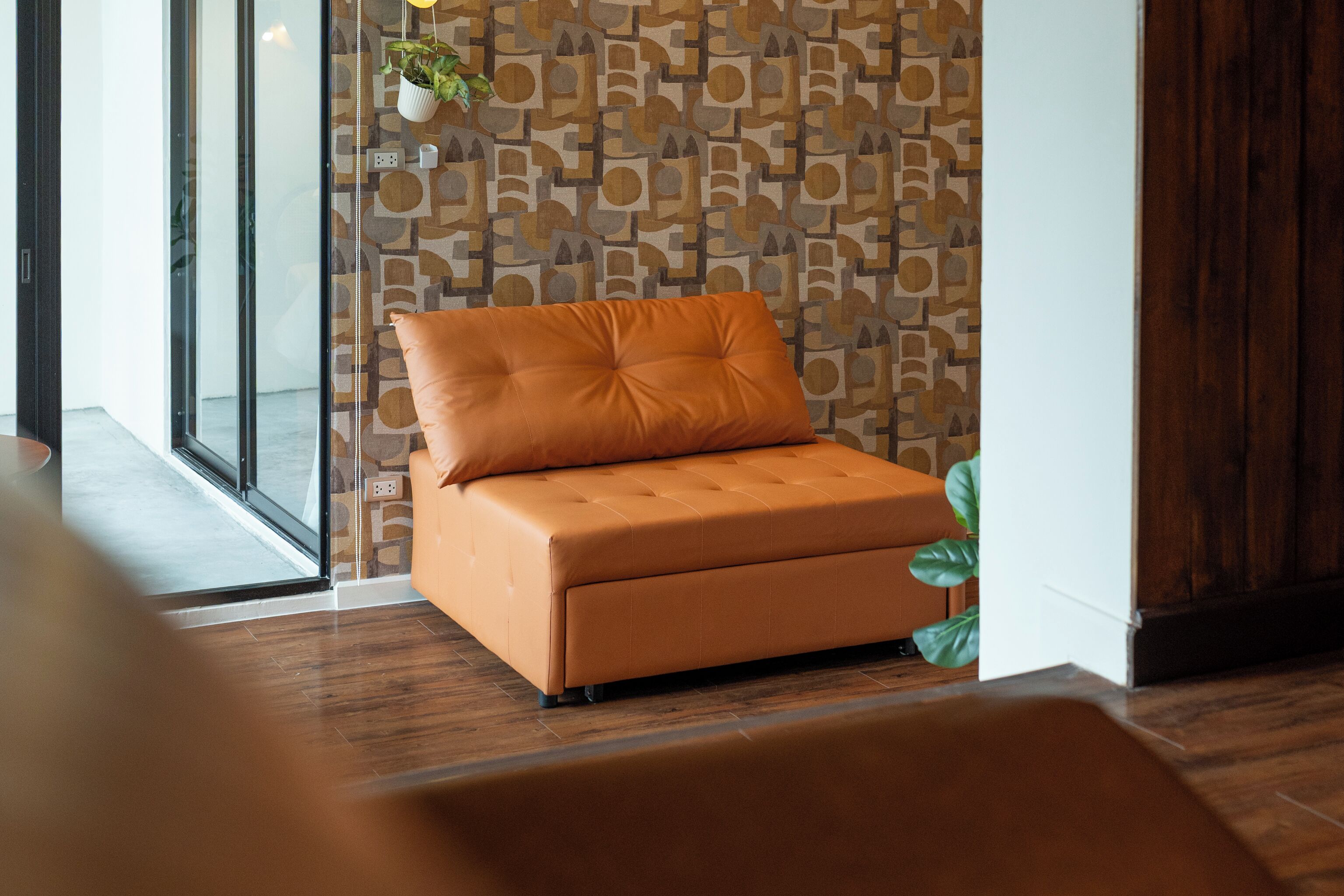 A modern room with a wooden floor, a glass door, and a patterned wall.