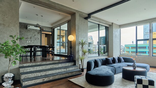A modern living room with a sectional sofa, a coffee table, and a staircase leading to an upper level. - 5loft Anti-Hotel, Silom, Bangkok (Bangkok)