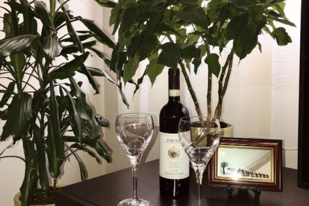 A table with a bottle of wine, two wine glasses, and a framed picture.