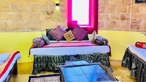 Ein Zimmer mit einem Bett, einem kleinen Tisch, einem gemusterten Teppich und einem Fenster mit pinkfarbener Umrandung.