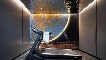 A treadmill in a room with a space-themed mural on the wall.