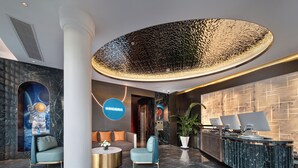 Un vestíbulo moderno con mostrador de recepción, zona de estar y un gran techo decorativo.