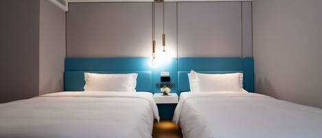 A hotel room with two beds, a nightstand with a lamp, and a wall-mounted light fixture.