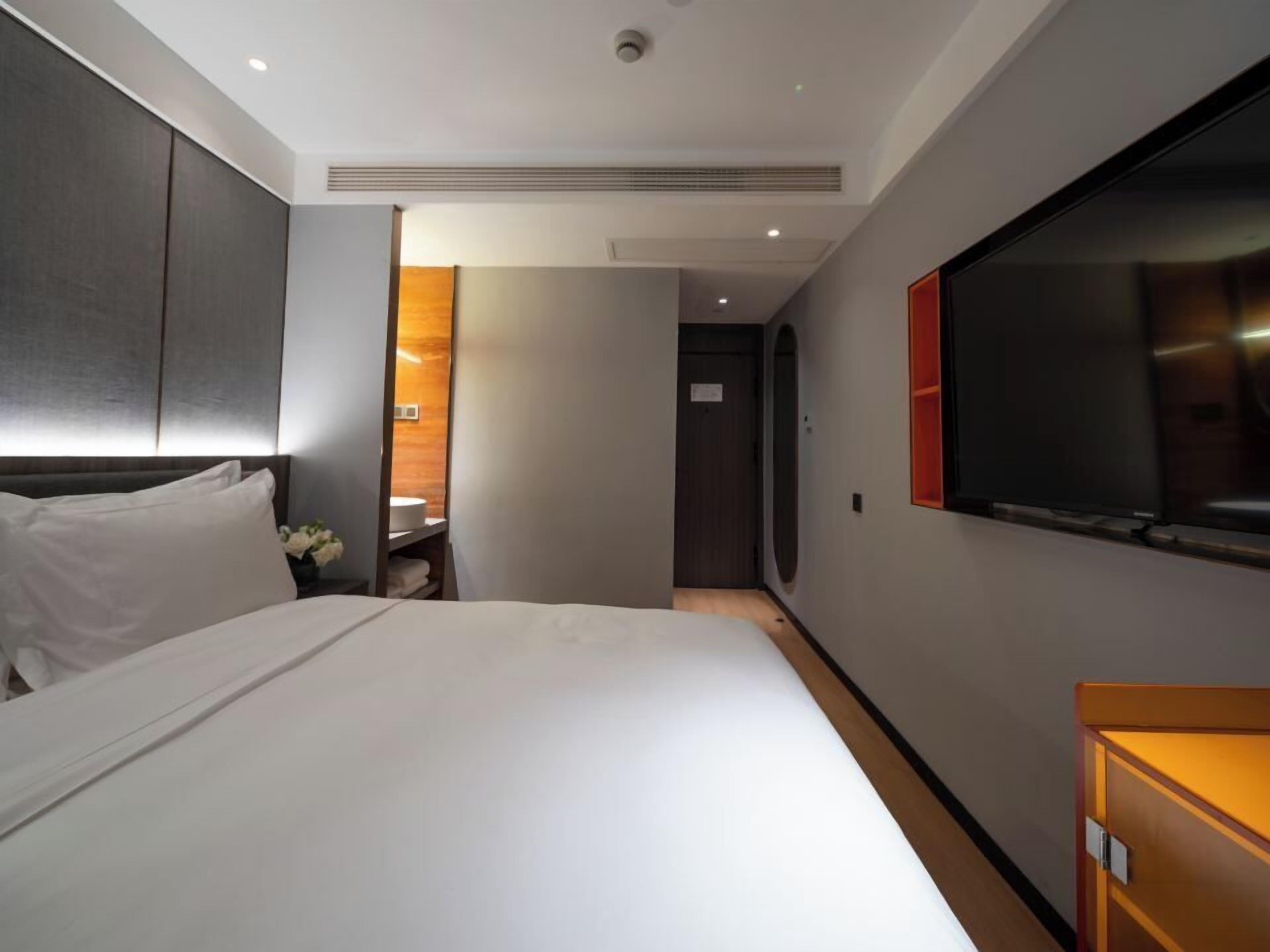 Et moderne hotelværelse med en stor seng, et fjernsyn og et træskab.