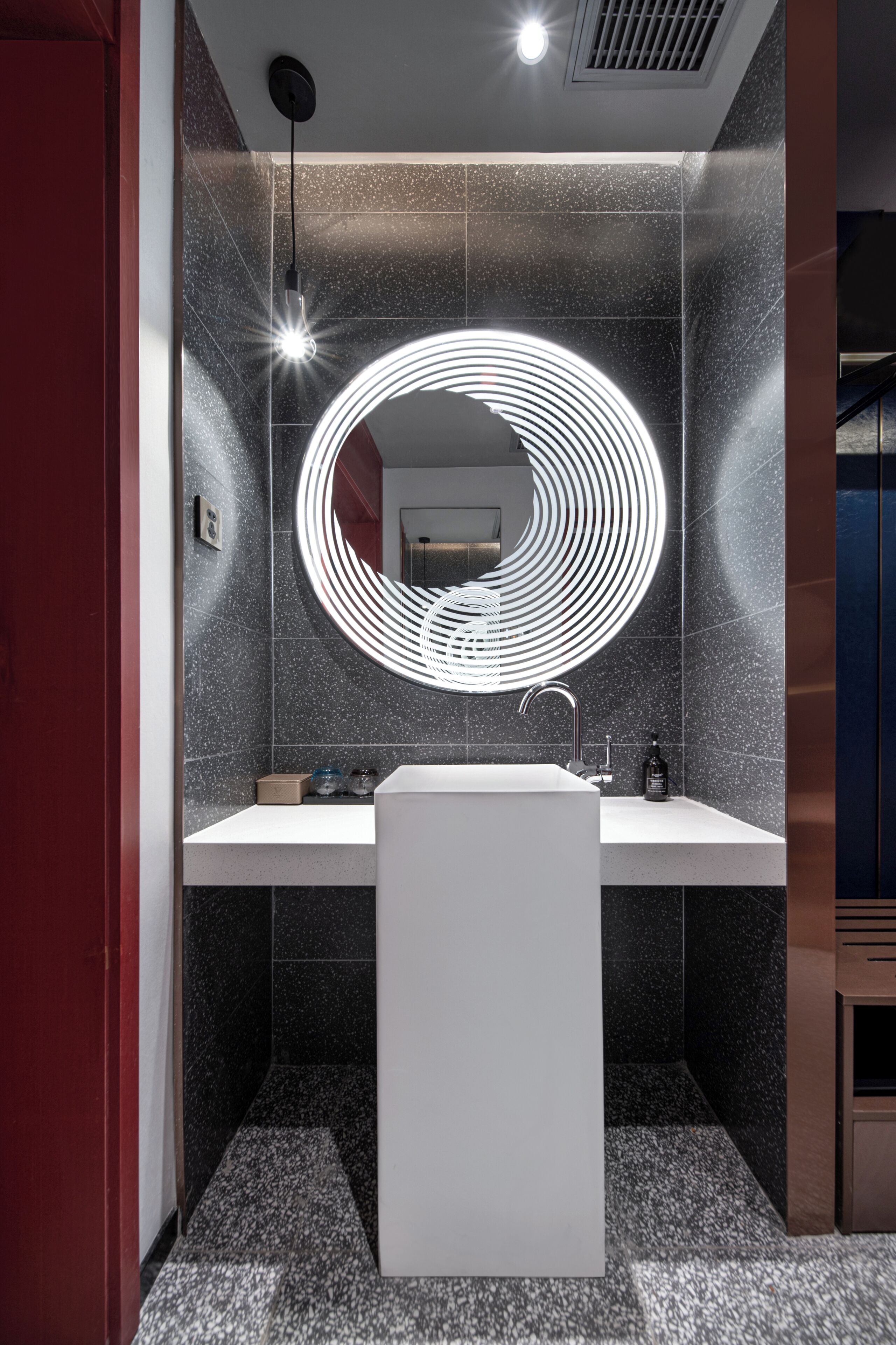 A modern bathroom with a circular mirror, a white sink, and a shower area.