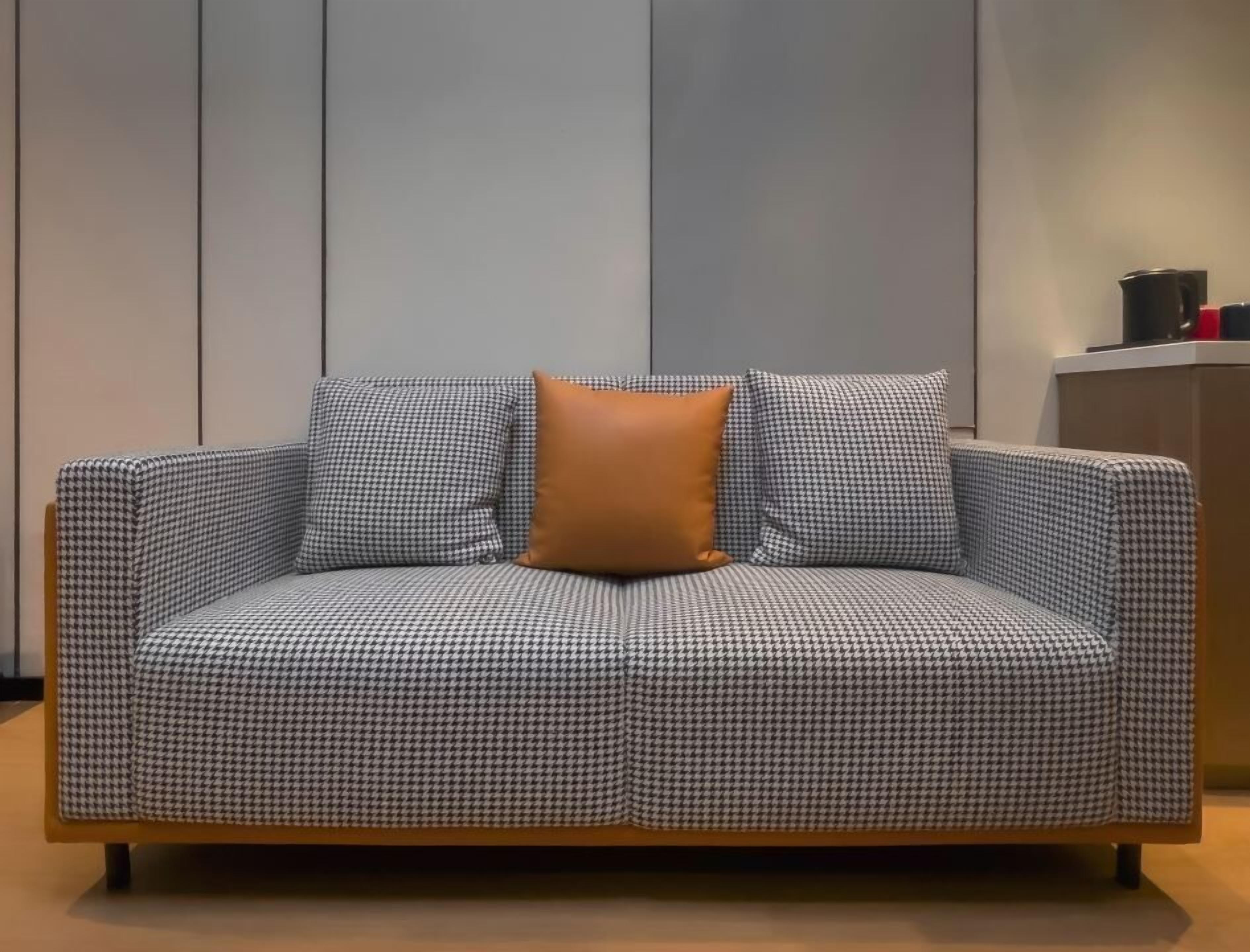 Ein Sofa mit Hunde-Zahn-Muster und einem einzelnen braunen Kissen in einem modernen Innenraum.