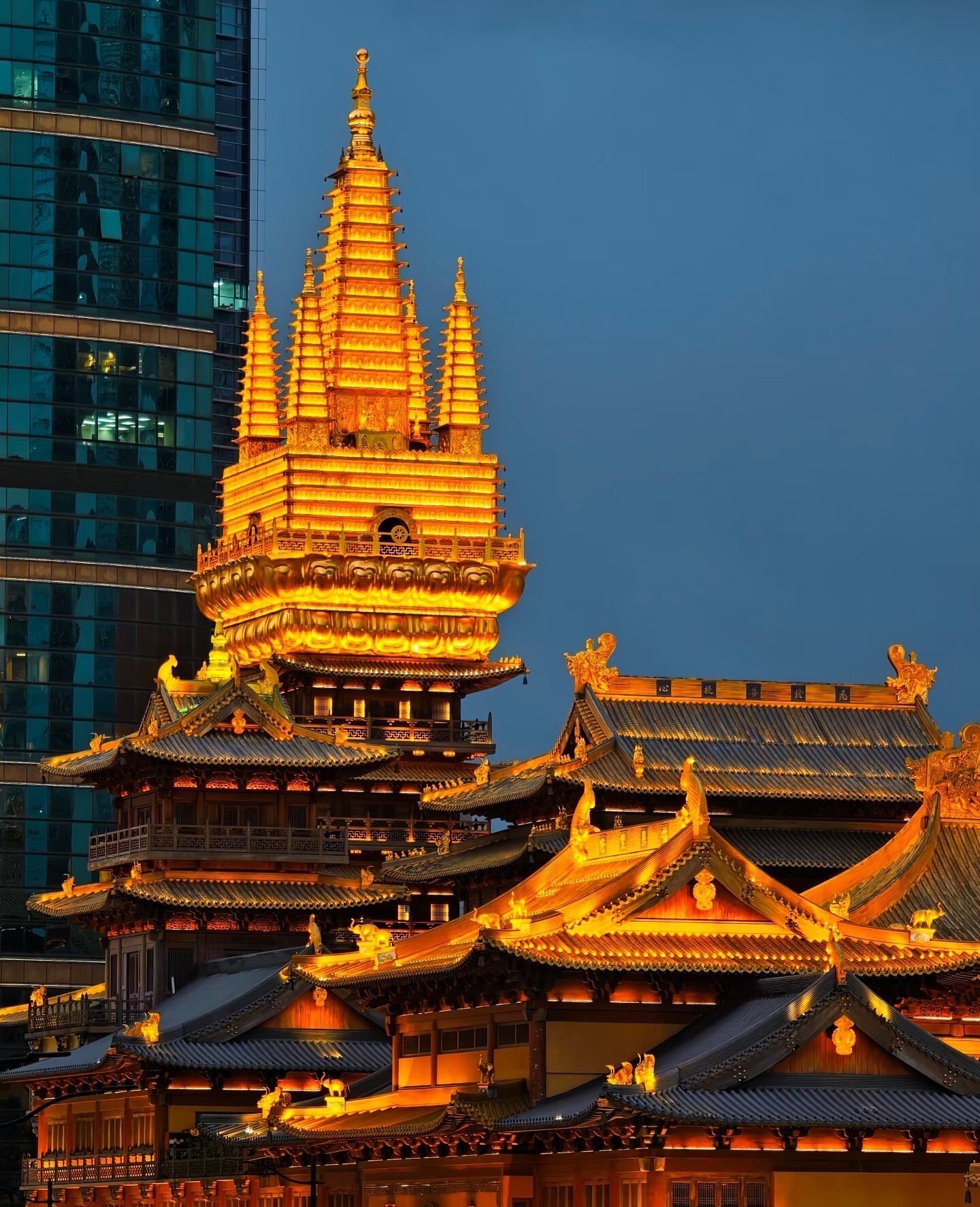 A traditional multi-tiered temple with ornate golden roofs and intricate architectural details, set against a modern city skyline.
