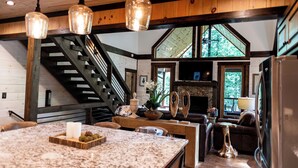 A spacious kitchen with a large island, wooden accents, and a stone fireplace. - Harmony River Retreat ~ Hot Tub ~ Fire Pit ~ Fish/Tube from the Backyard! (Ellijay)