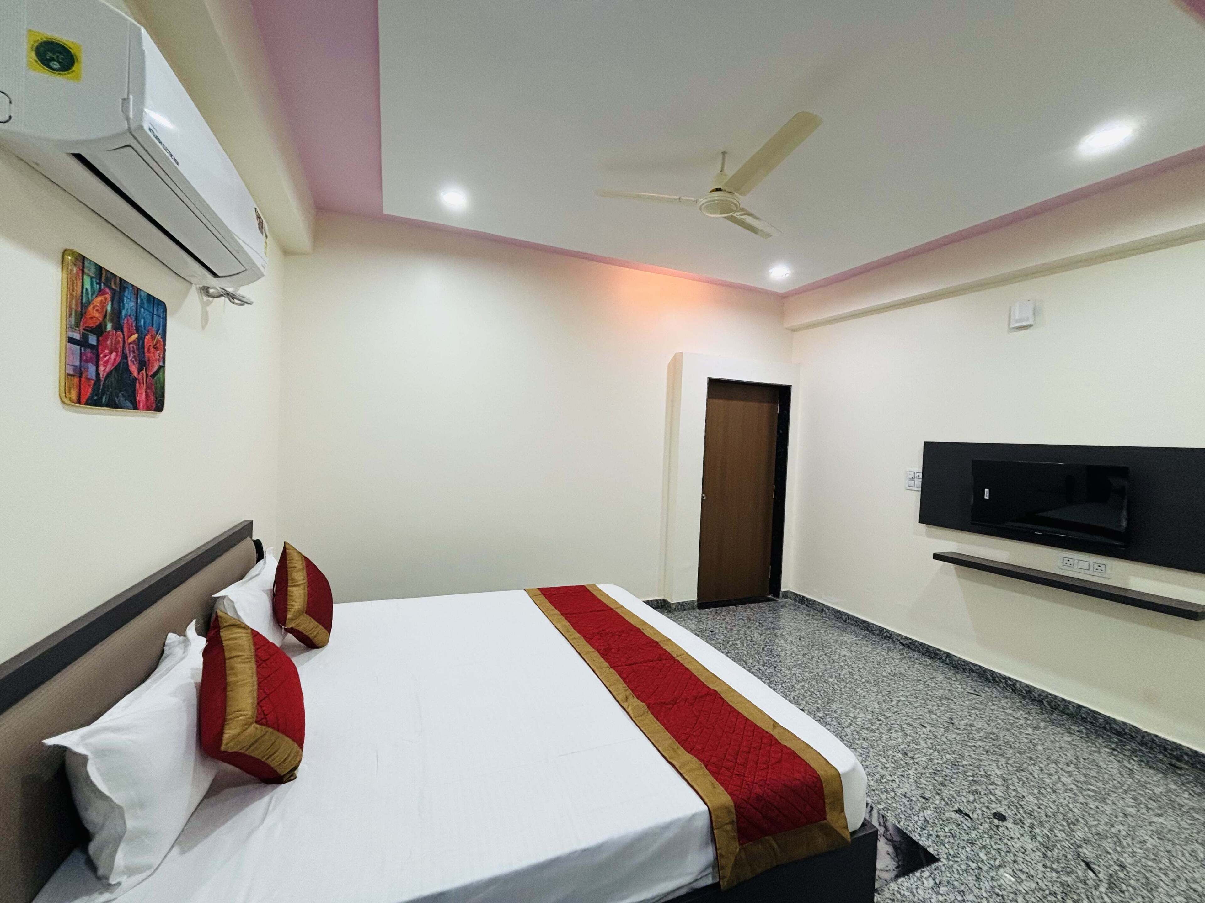 Une chambre d’hôtel équipée d’un lit, d’un ventilateur de plafond, d’un climatiseur, d’une télévision et d’une porte.