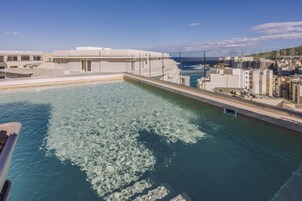 Una piscina techada, una piscina al aire libre, sombrillas