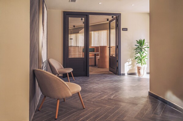A hotel lobby with a wooden herringbone floor, a seating area with a chair, and a potted plant. - Hotel Ben Marsalforn, Affiliated By Meliá (Zebbug)