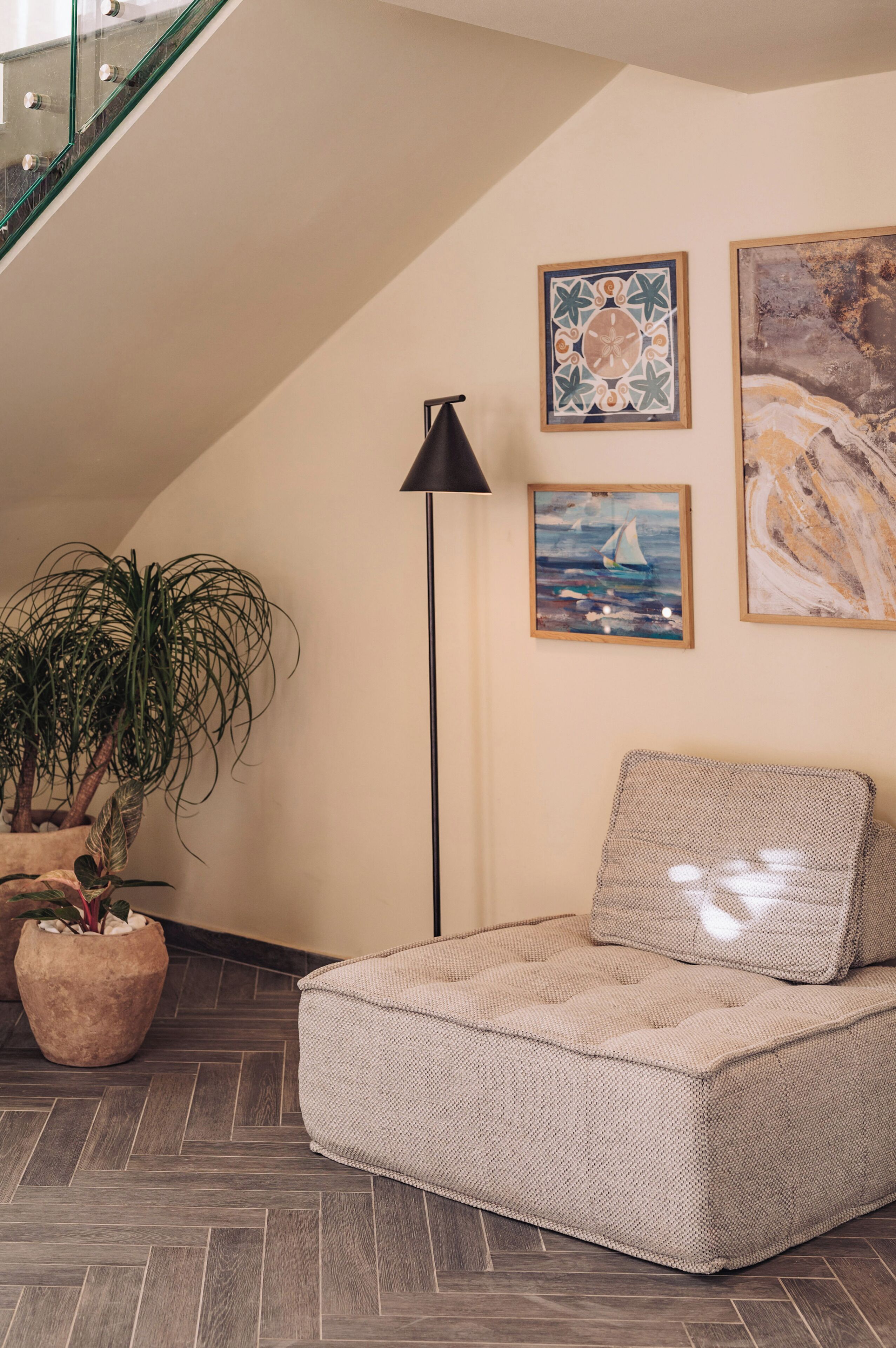 A cozy living area with a cushioned sofa, a potted plant, and artwork on the walls.