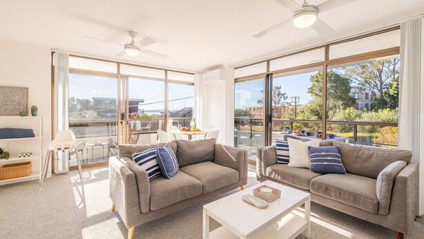 A spacious living room with two sofas, a coffee table, and a balcony with a dining area.