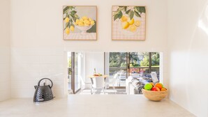 A modern kitchen with a kettle, a fruit bowl, and two framed paintings of lemons on the wall.