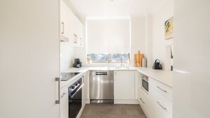 A modern kitchen with white cabinetry, stainless steel appliances, and a window providing natural light.