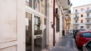 A narrow street with parked cars and a building with a glass door and windows. - Rifugio Pugliese by Wonderful Italy (Bari)