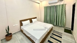Een hotelkamer met een bed, een plafondventilator, een airconditioning, een plant in pot en een kamerkleed.